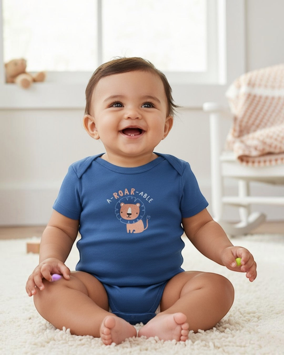 Baby wearing a blue onesie with a lion design and text, sitting on a carpeted floor.