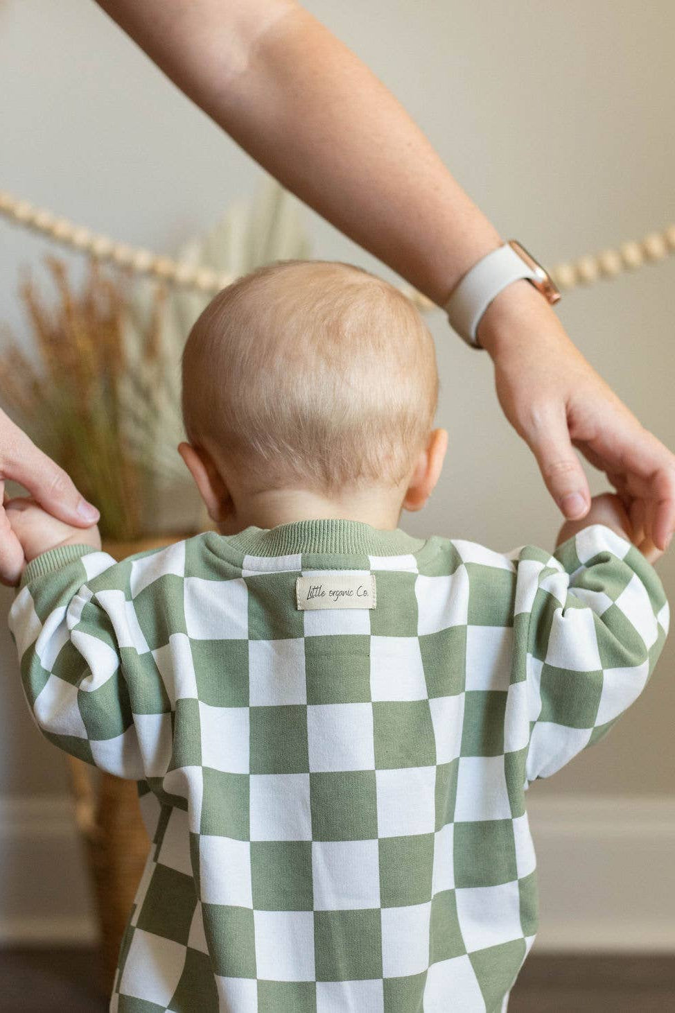 Baby wearing a green and white checkered outfit with a blurred background