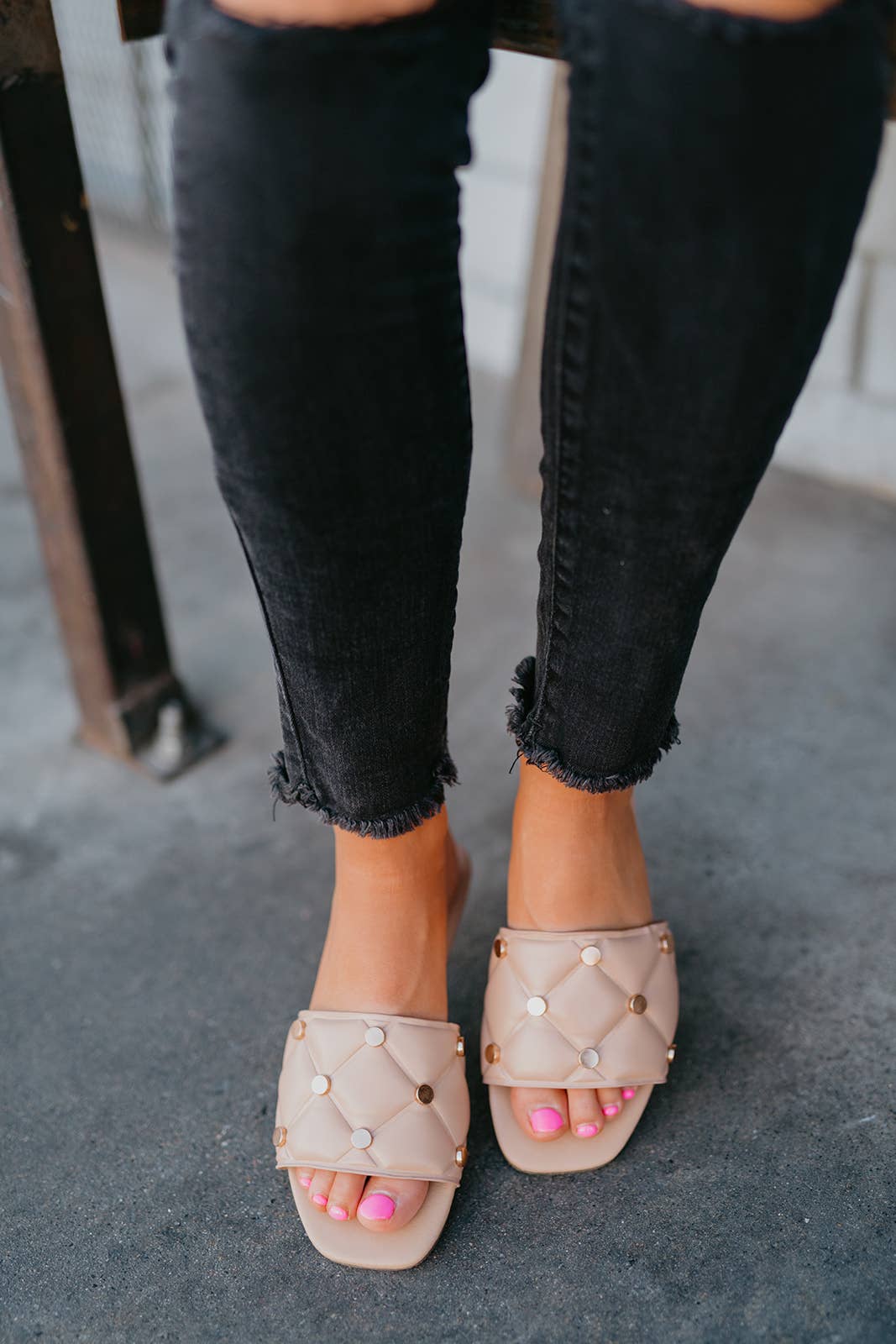 Close-up of feet wearing beige sandals with pearl embellishments on a blurred background