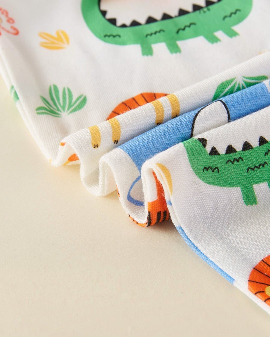 Set of colorful fabric swatches with dinosaur patterns on a beige background