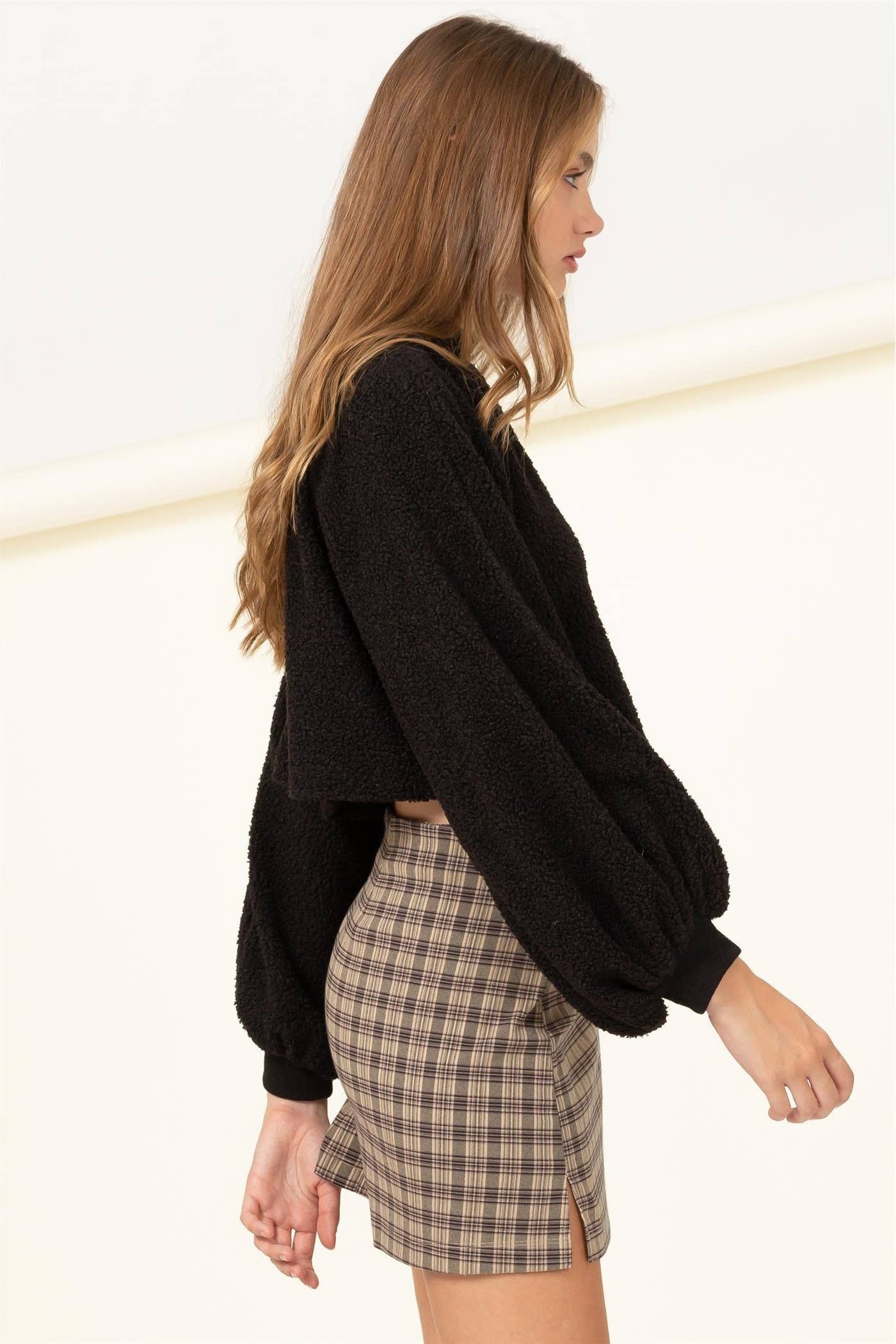 Woman wearing a black sweater and plaid skirt on a white background