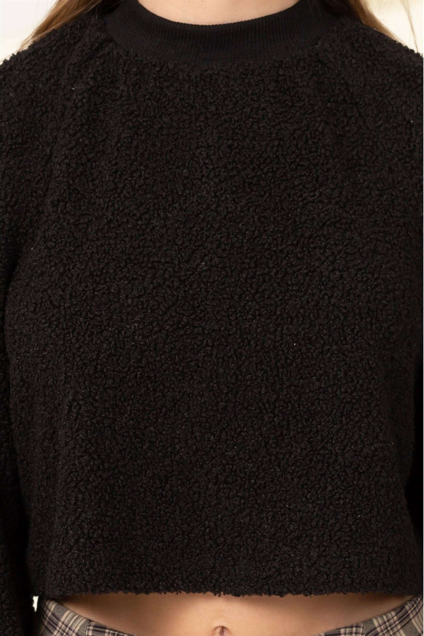 Black textured sweater worn by a person on a white background