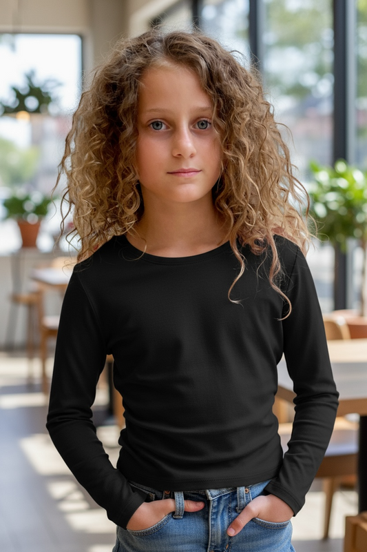 Young girl wearing a black long-sleeve shirt and blue jeans indoors.
