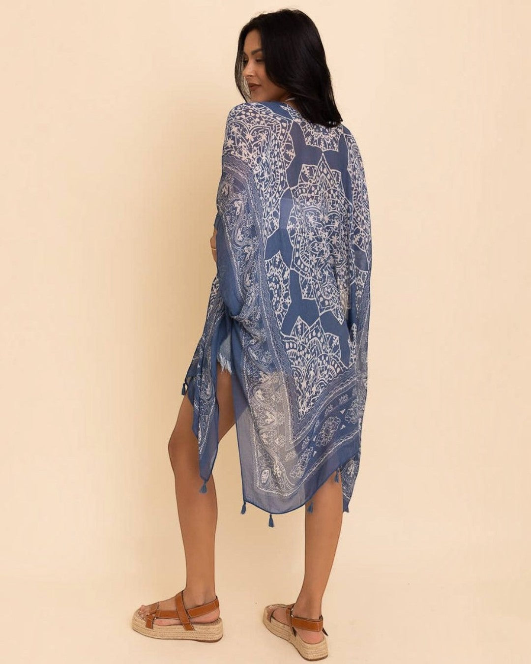 Woman wearing a blue patterned dress against a beige background