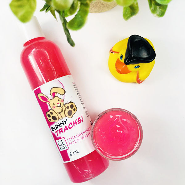 Bunny Tracks Shimmering Body Wash in a transparent bottle and cup of our pink bunny tracks body wash against a white background