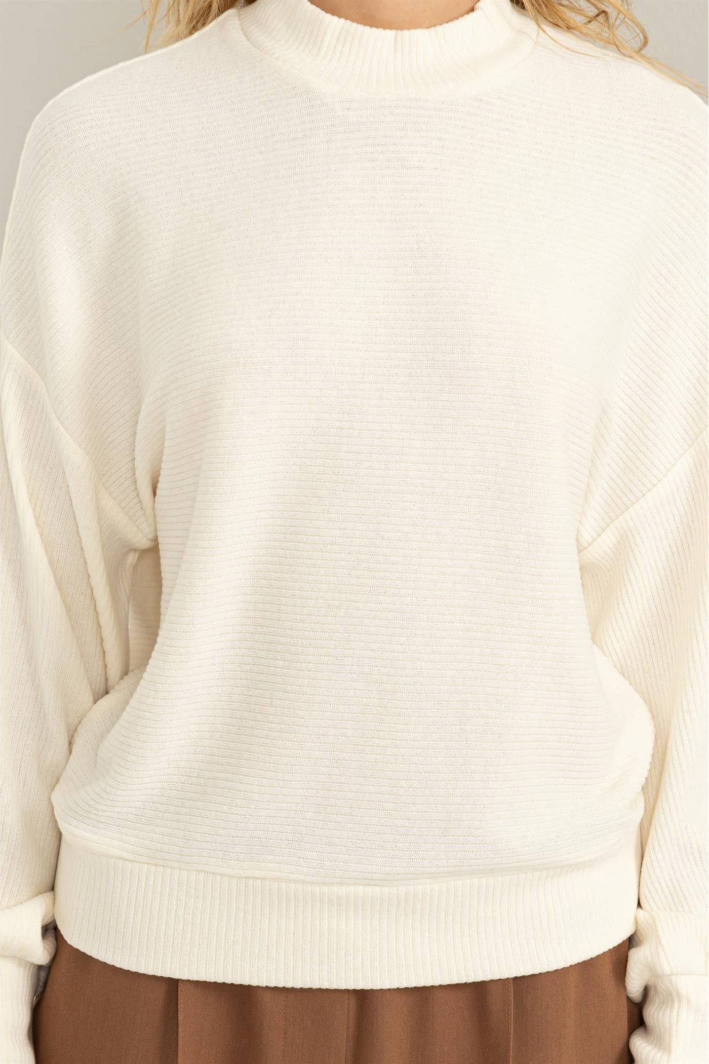 Beige sweater worn by a person on a white background