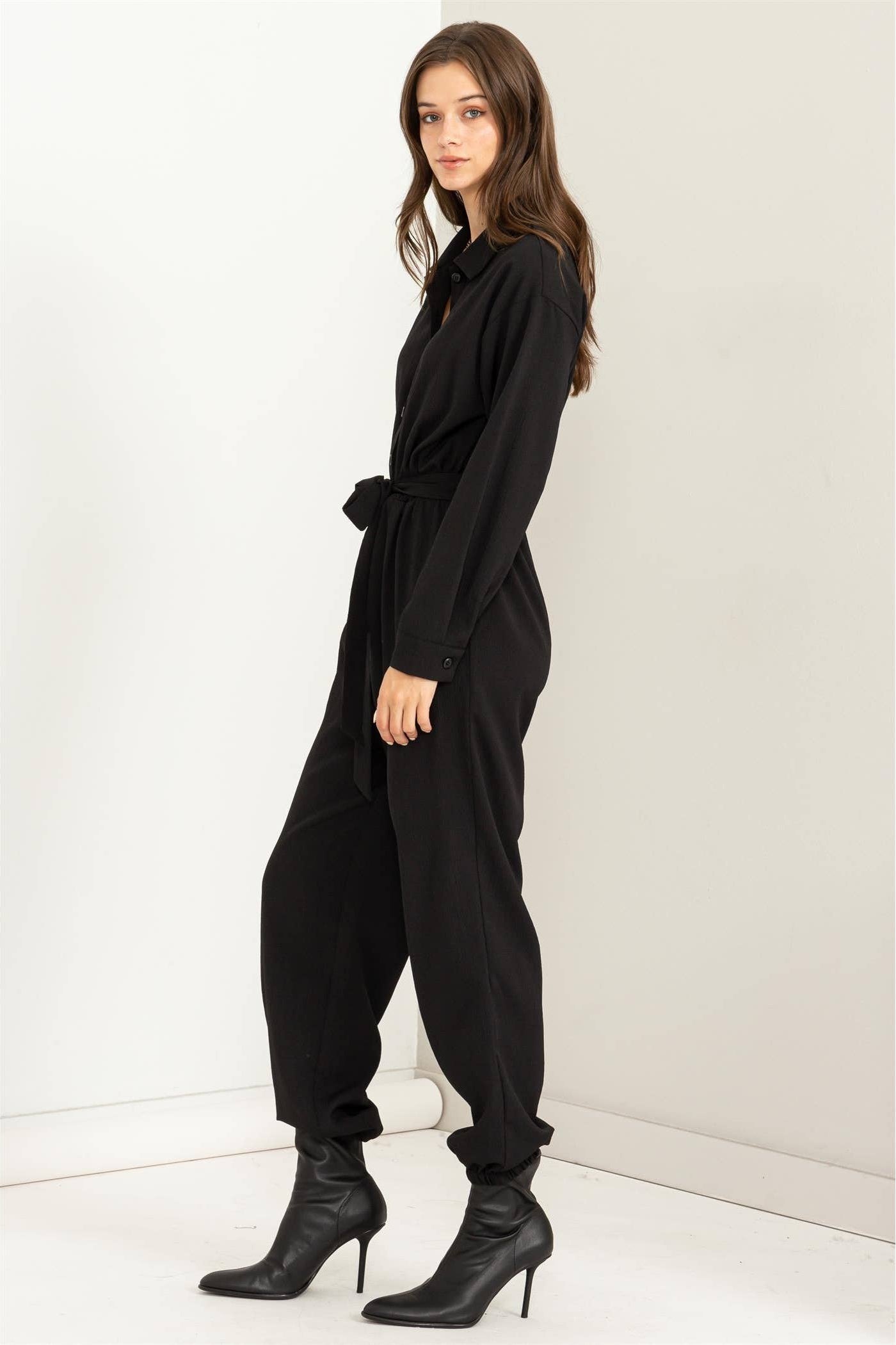 Woman wearing a black jumpsuit against a white background