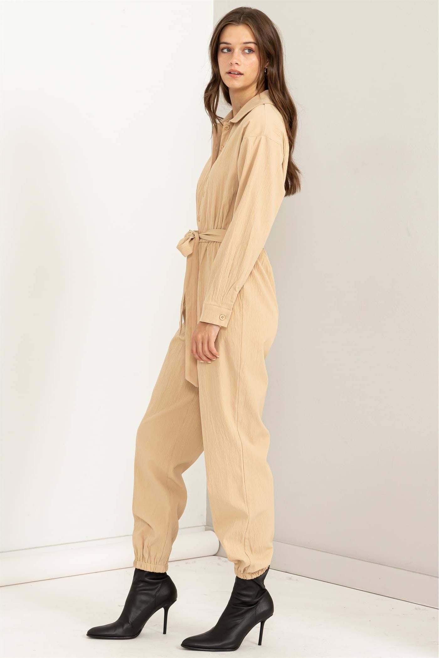 Woman wearing a beige jumpsuit against a white background