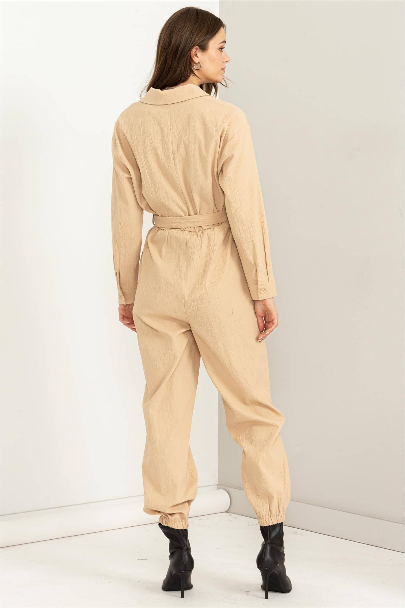 Woman wearing a beige jumpsuit against a white background