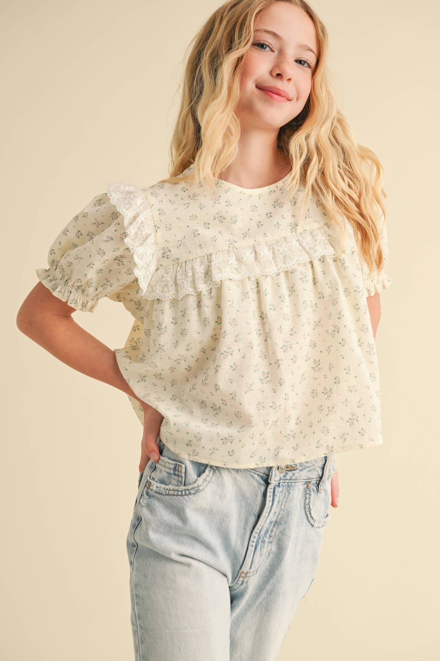 Woman wearing a floral blouse and jeans on a beige background