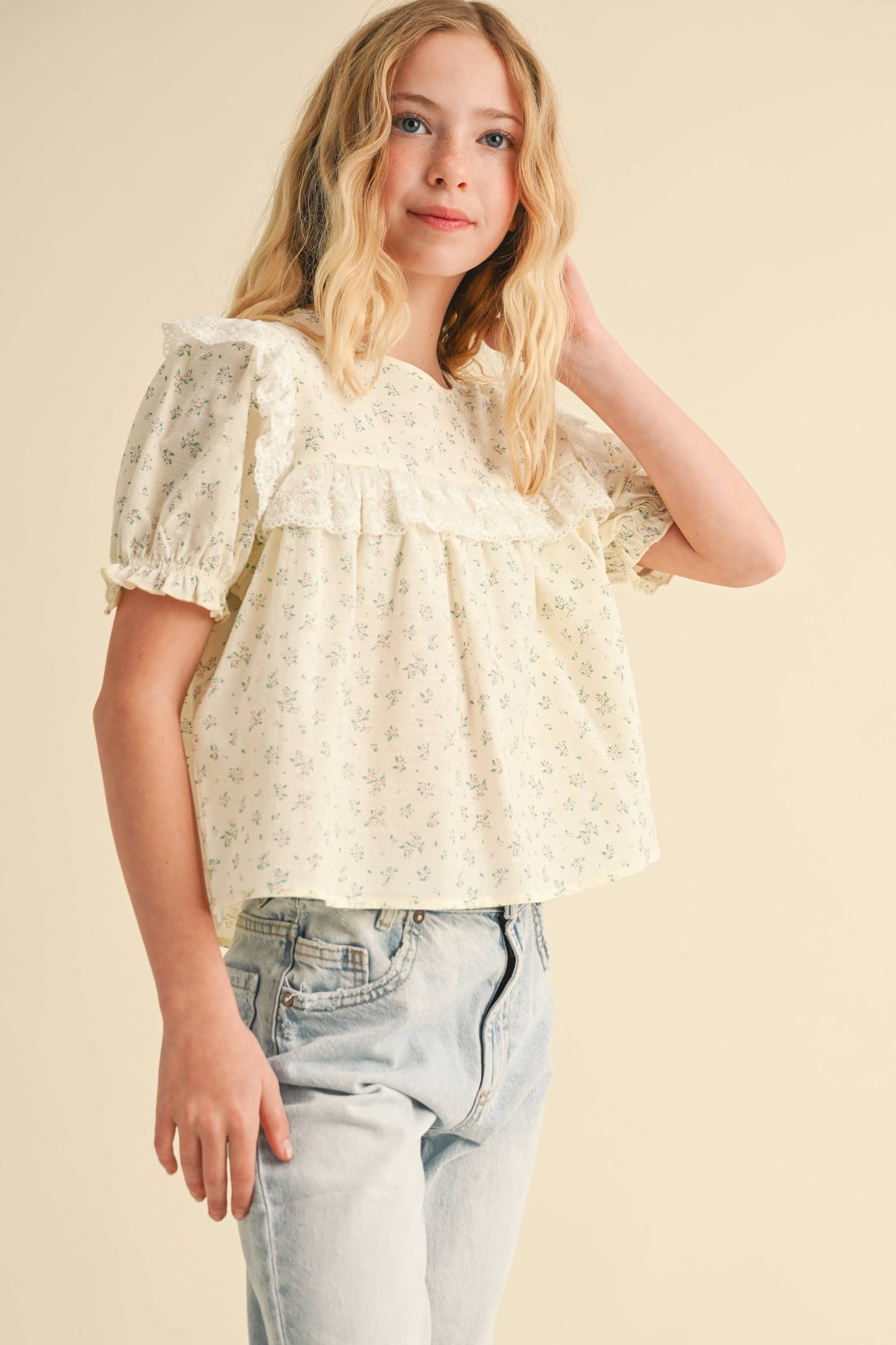 Young girl wearing a floral blouse and jeans on a beige background