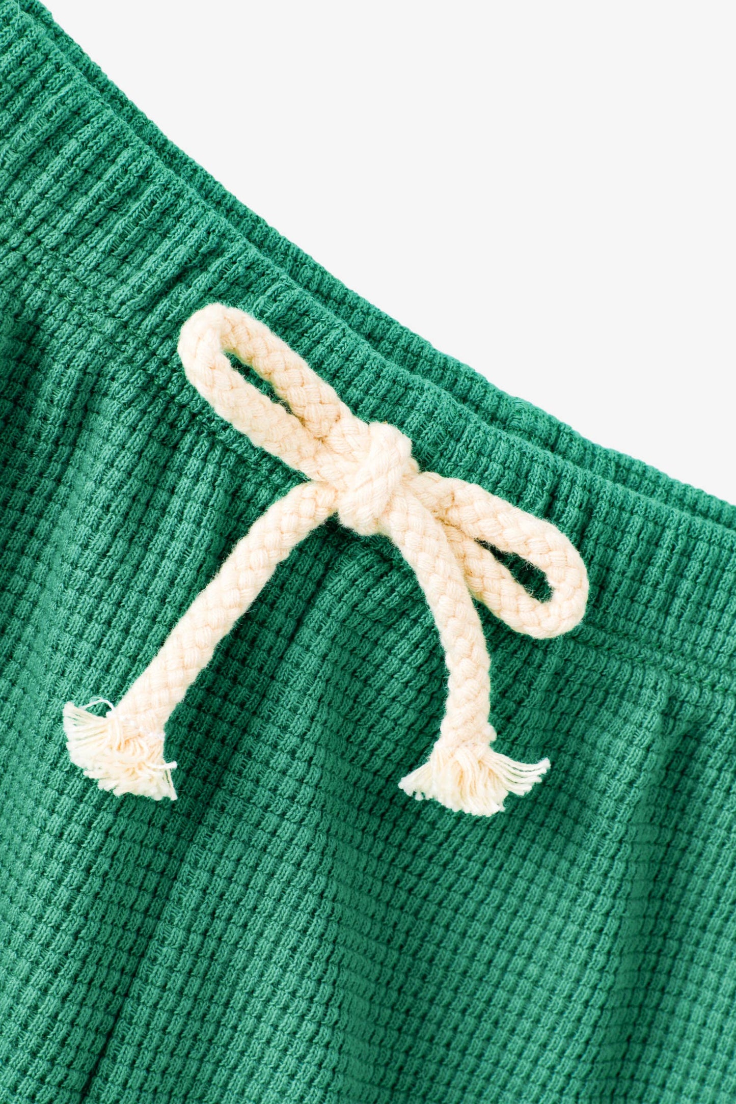 Green textured fabric with a white drawstring on a light gray background