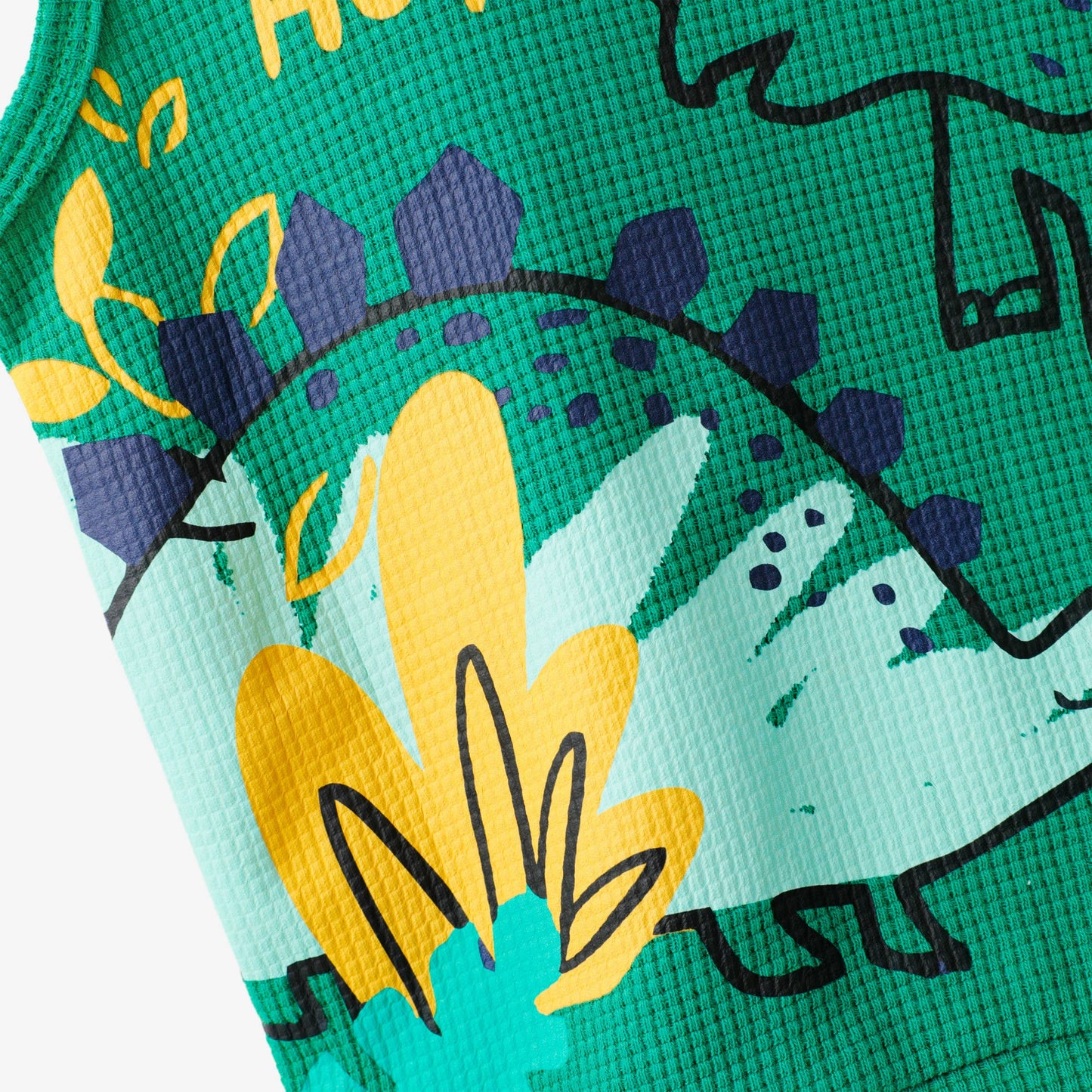 Close-up of a green fabric with yellow dinosaur illustrations and text.