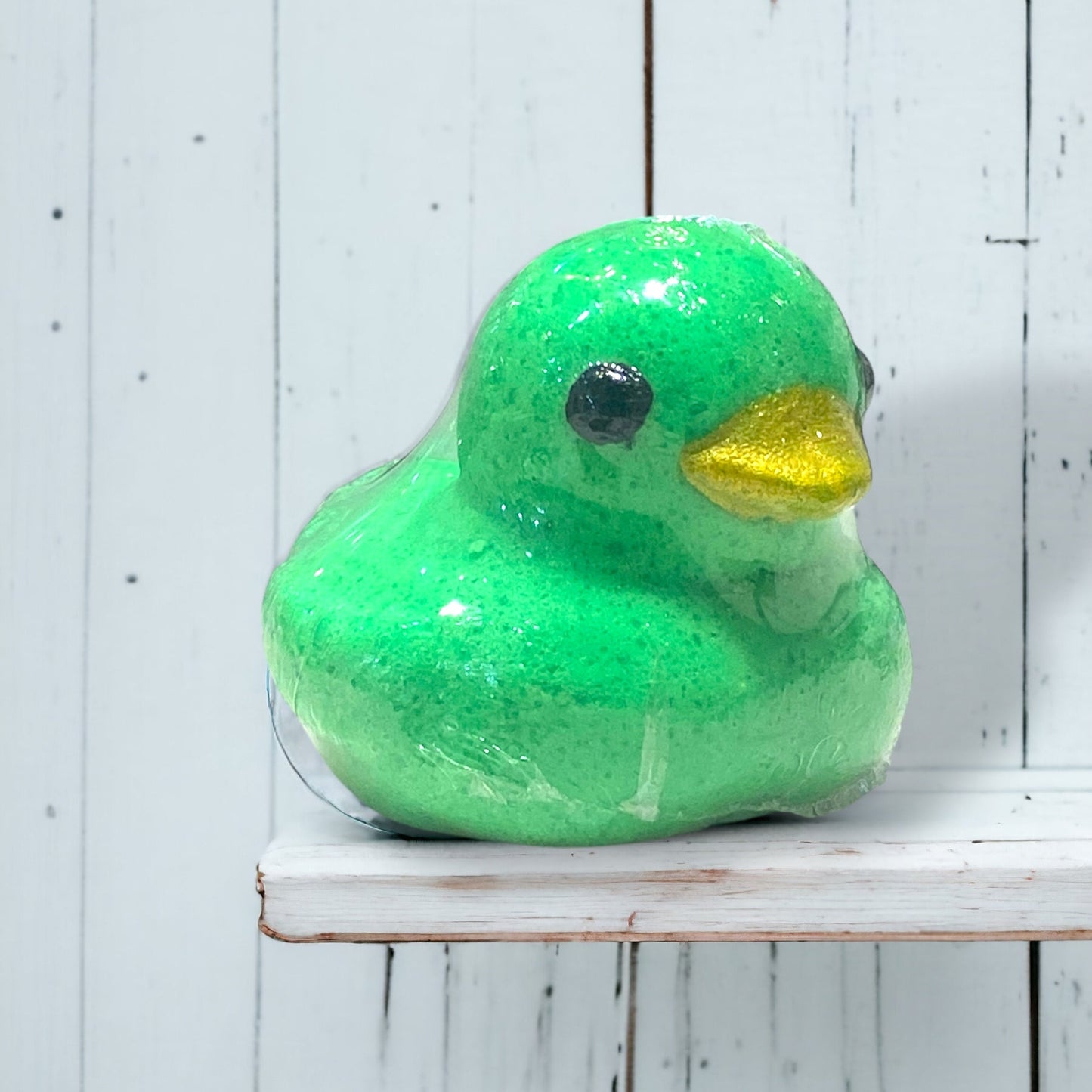 Green rubber duck on a white wooden surface
