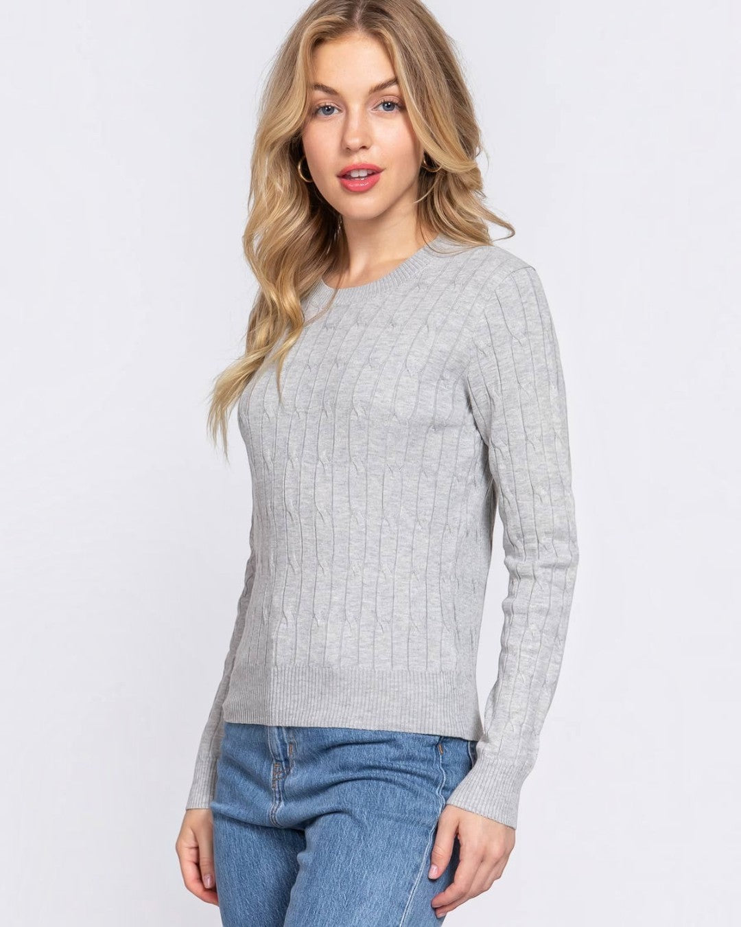 Woman wearing a gray sweater and blue jeans on a white background