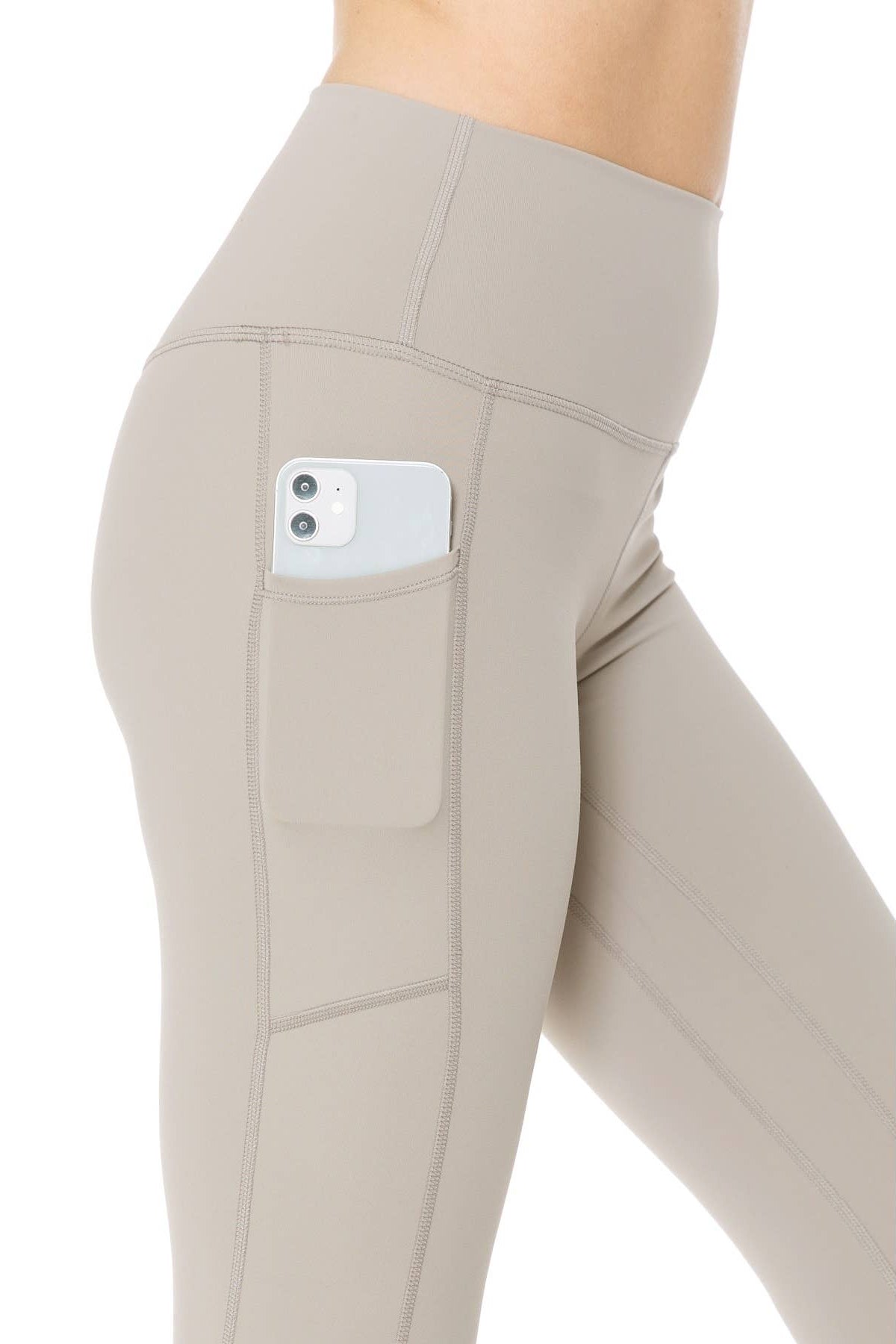 Beige leggings with a pocket holding a phone on a white background