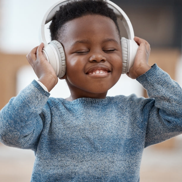 Child wearing headphones and smiling with a blurred background