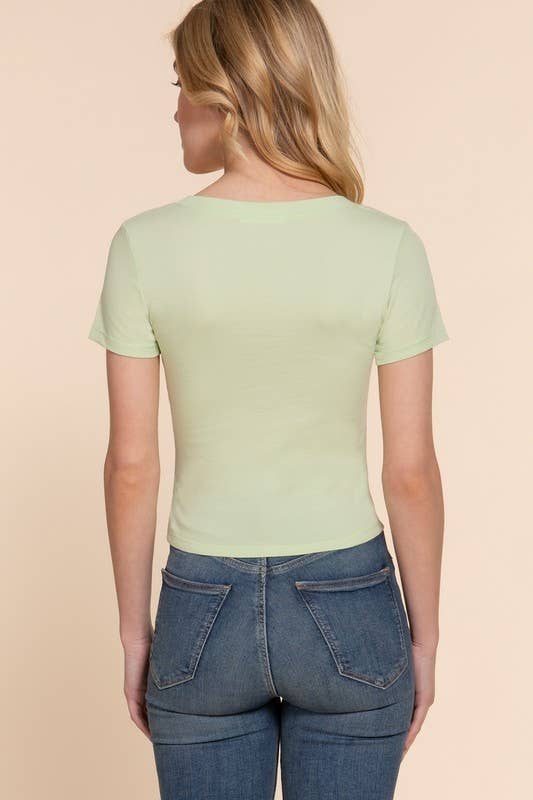 Woman wearing a light green t-shirt and blue jeans on a beige background