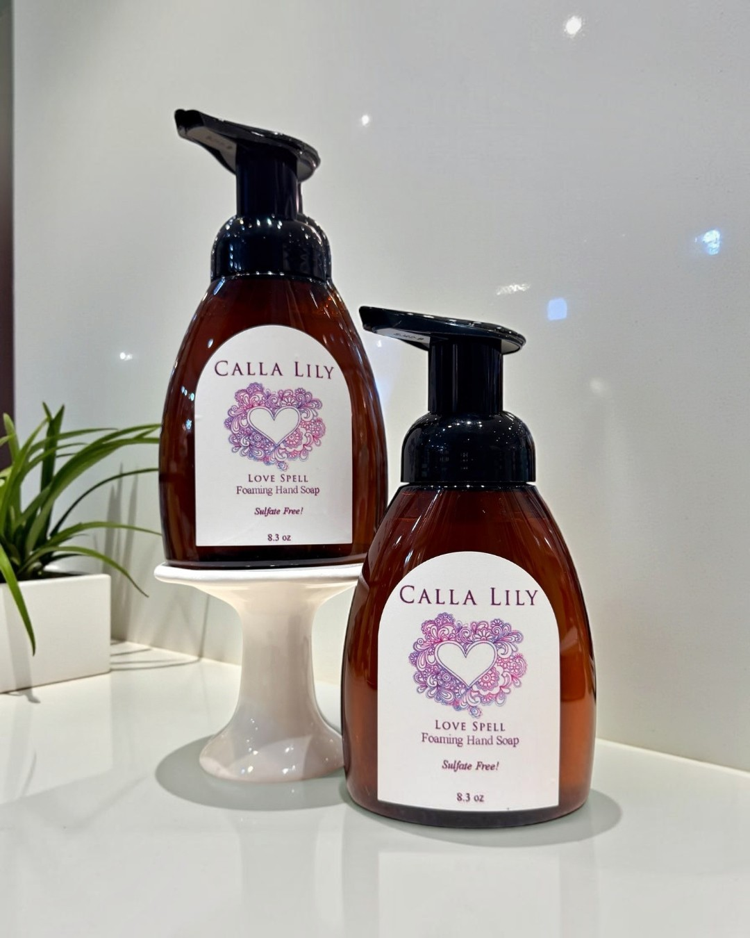 Calla Lily Cosmetics + CL kids Love Spell foaming hand soap in two 8oz amber pump bottles on a white display stand.