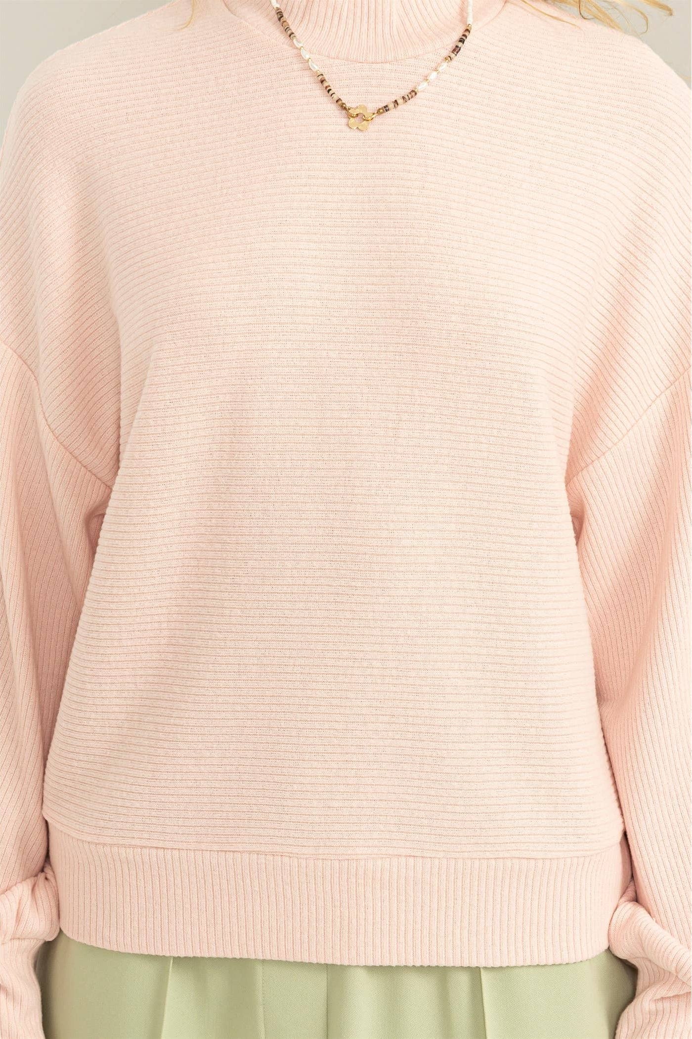 Pink sweater worn by a person on a white background