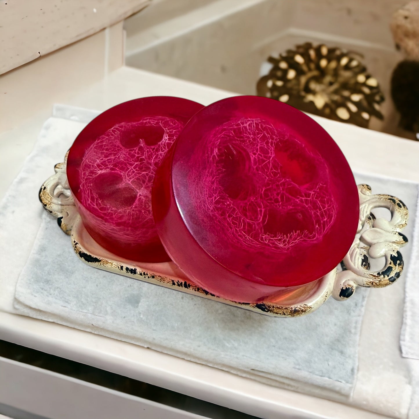 Two pink soaps on a decorative tray with a blurred background