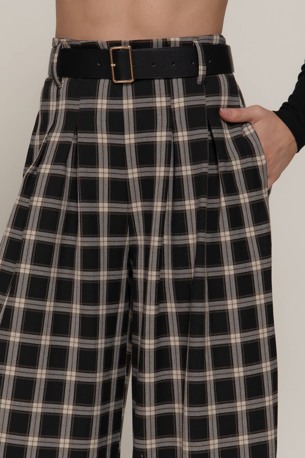 Black and white plaid pants with a belt on a plain background