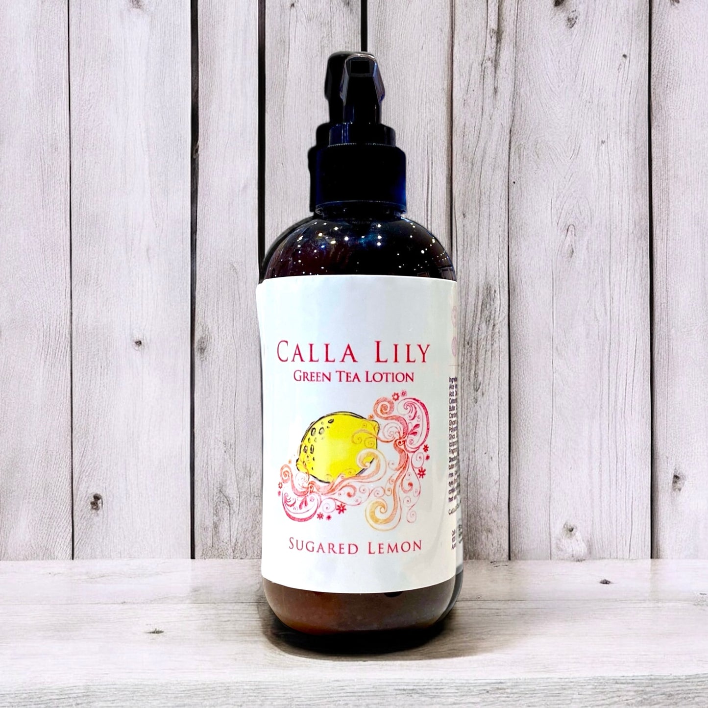 Bottle of Calla Lily Green Tea Lotion with a lemon design on a wooden background
