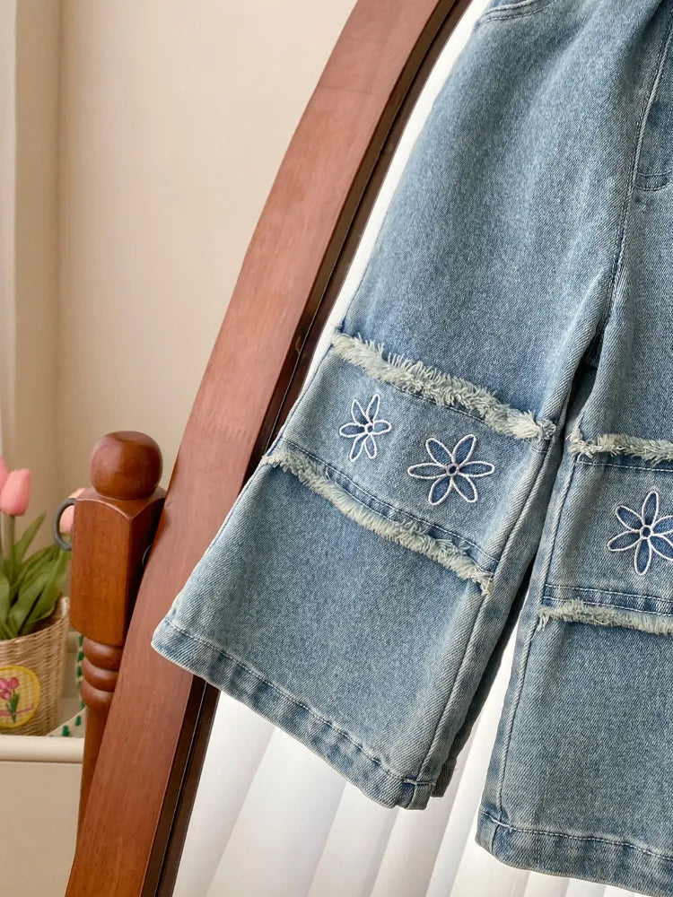 Denim pants with floral embroidery on a wooden chair