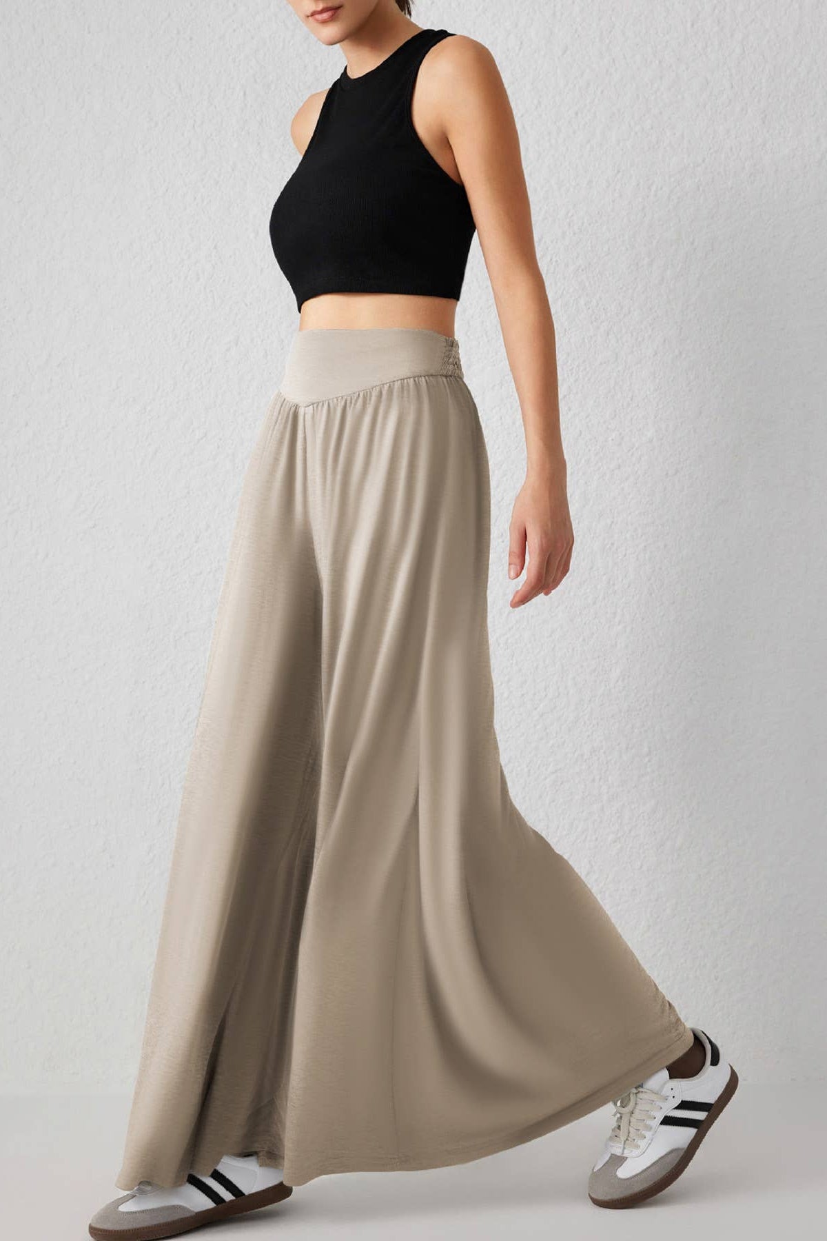 Person wearing a black crop top and beige wide-leg pants on a plain background