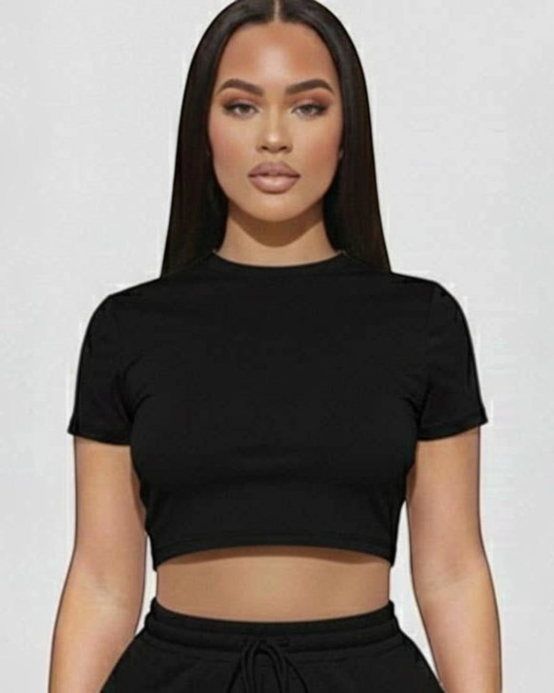 Woman wearing a black crop top and shorts set on a white background