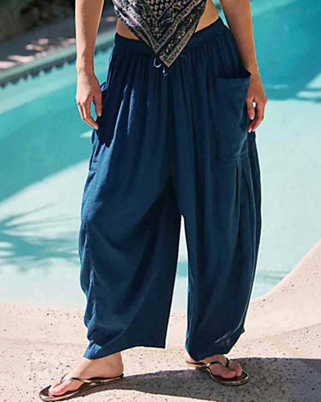 Person wearing blue harem pants by a pool