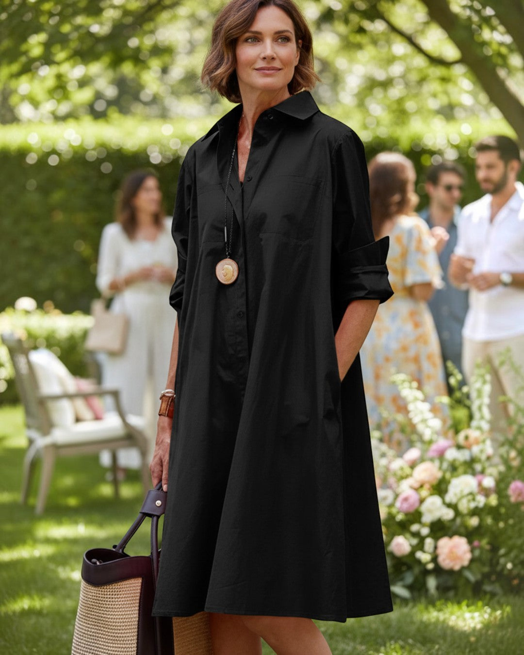 Woman wearing a black Calla Lily Cosmetics + CL kids long sleeve shirt dress with a lapel collar in a garden setting.