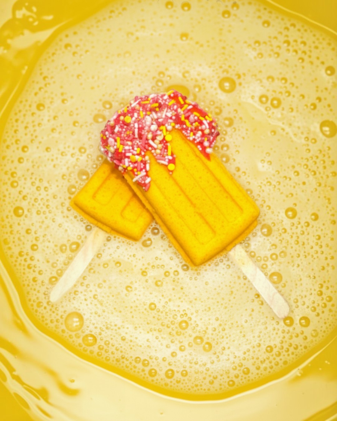 Calla Lily Cosmetics + CL kids yellow pineapple popsicle bath bomb with pink sprinkles dissolving in bath water