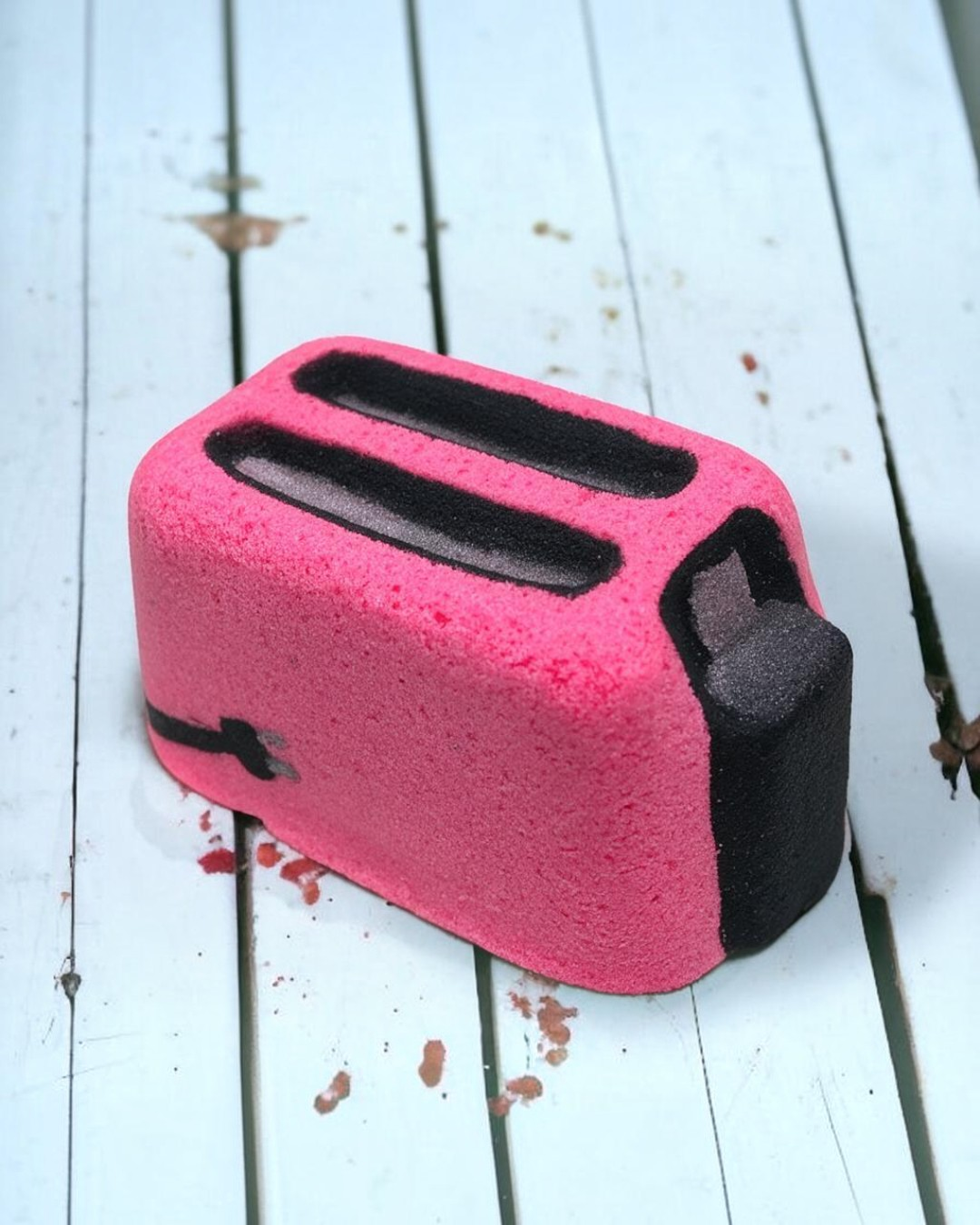 Calla Lily Cosmetics + CL kids pink toaster-shaped bath bomb with strawberry scent on a white wooden surface