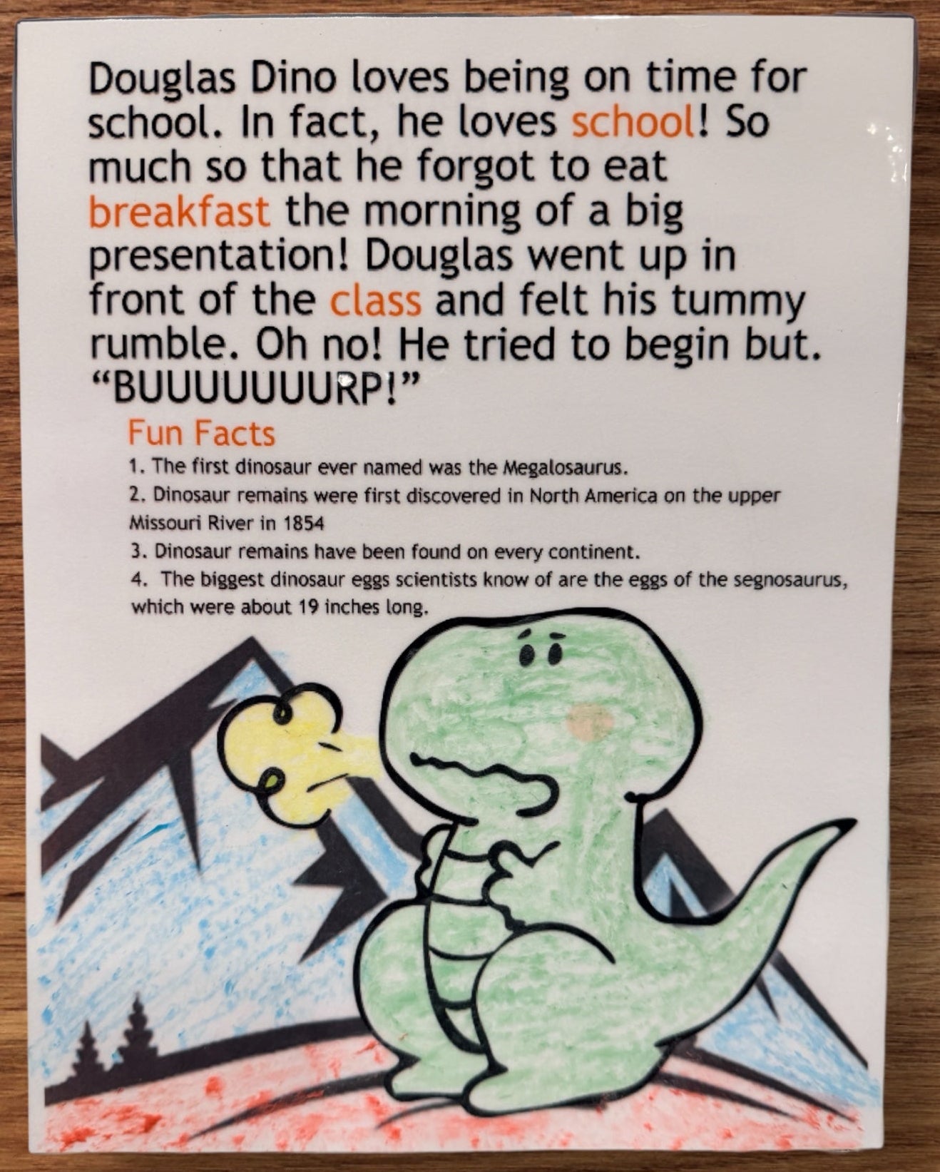 Children's book page with a cartoon dinosaur and text on a wooden surface