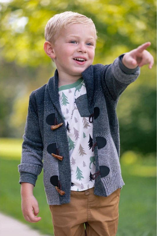 Child wearing a gray cardigan with nature-themed design outdoors