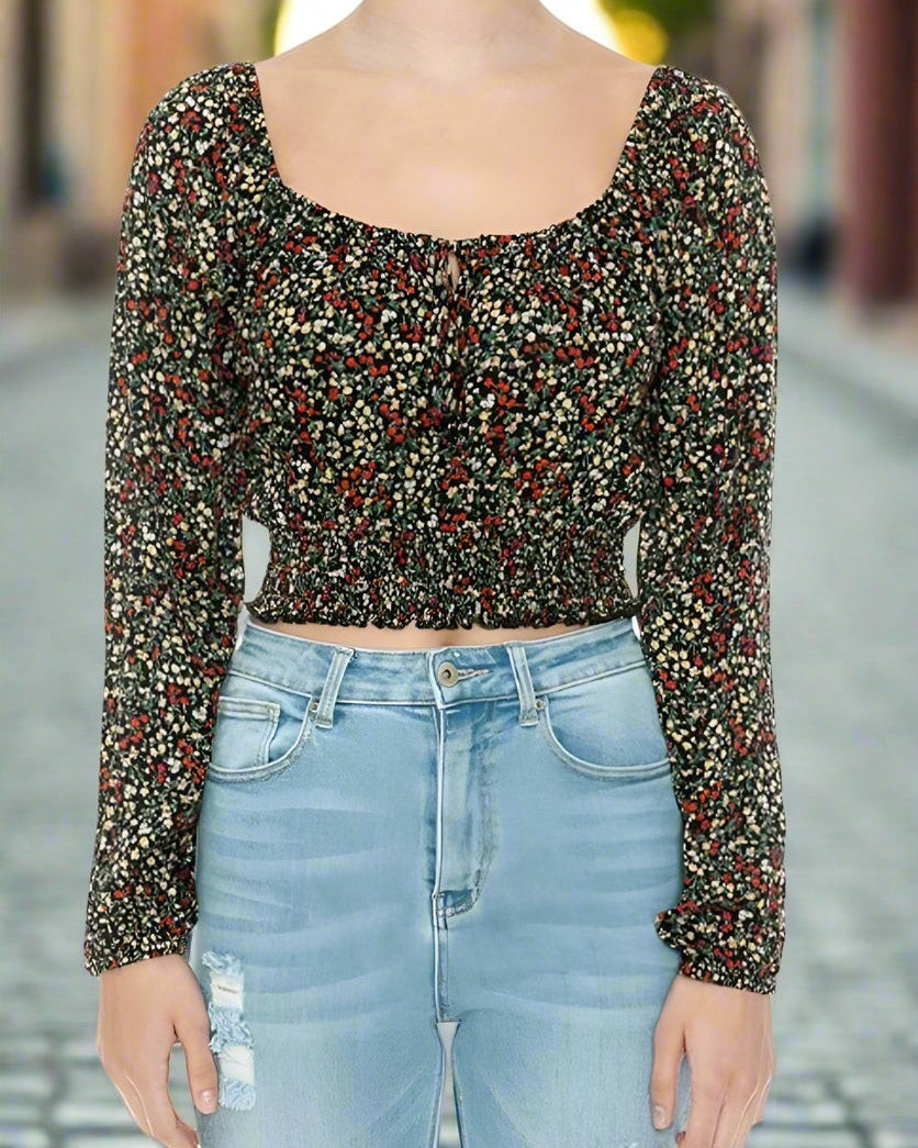 Person wearing a patterned long-sleeve top and light blue jeans on a blurred street background