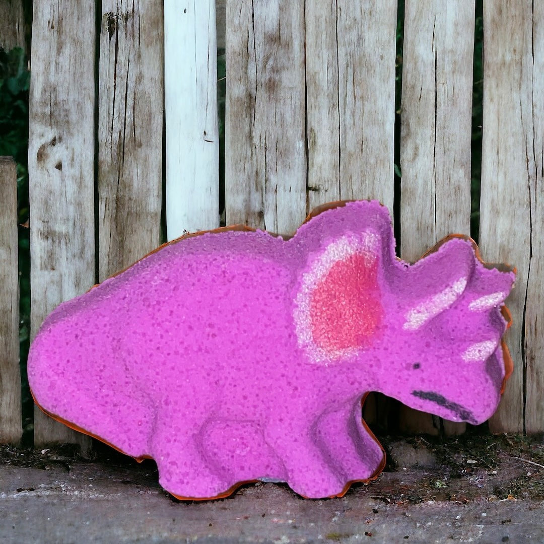 Pink dinosaur-shaped object against a wooden fence background