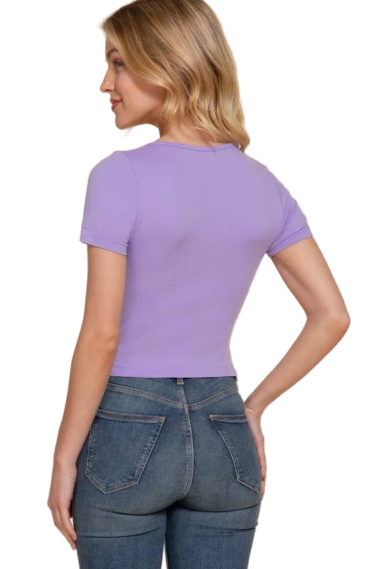 Woman wearing a purple t-shirt and blue jeans on a beige background