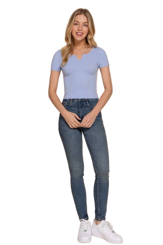 Woman wearing a light blue t-shirt and dark blue jeans on a beige background