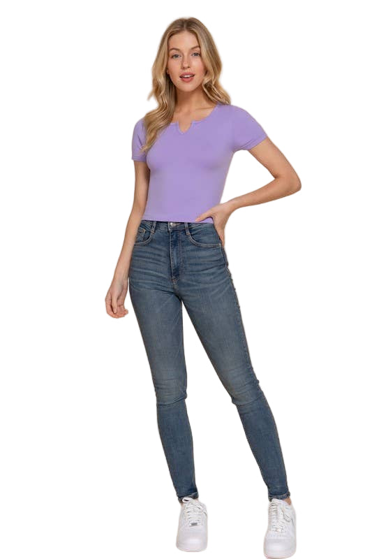 Woman wearing a purple top and blue jeans on a beige background