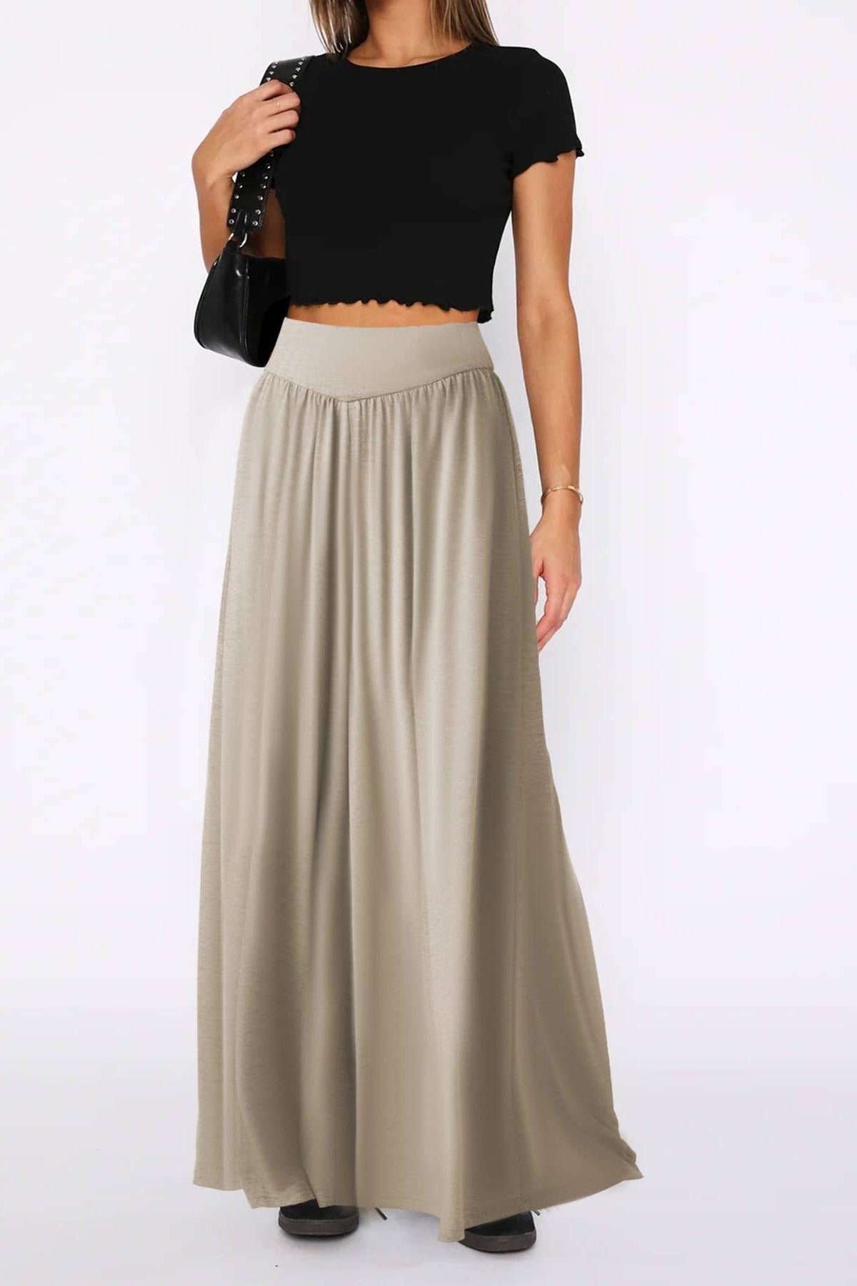 Person wearing a black top and beige long skirt on a white background