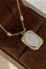 Gold necklace with a silver pendant on a brown textured surface