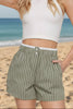 Woman wearing a white crop top and striped shorts against a plain background