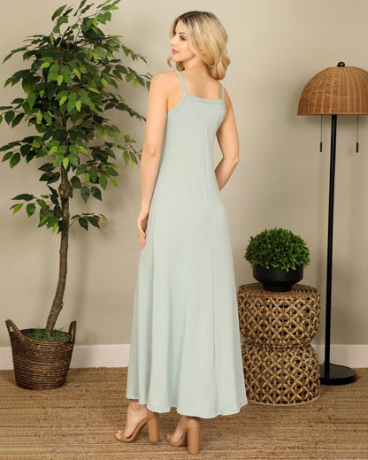 Woman wearing a light blue dress standing in a room with a plant and lamp.