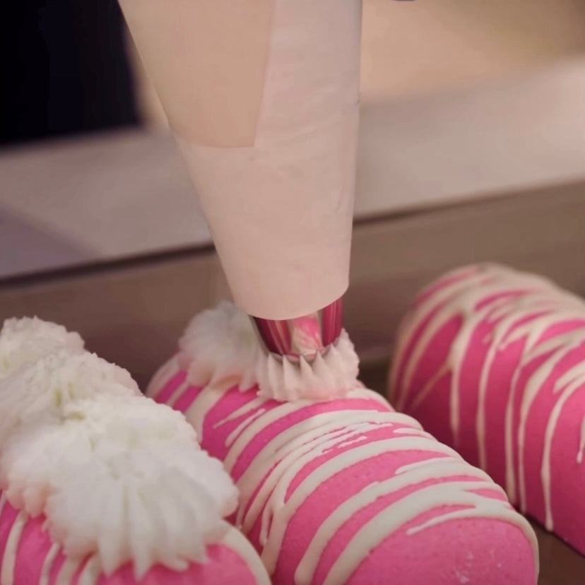 A set of pink twinkie bath bombs being topped with white frosting