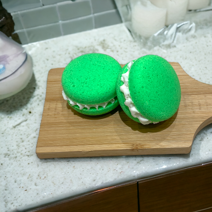 Two green dino burps bath cookies on a wooden paddle