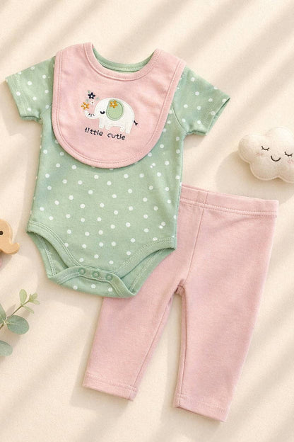 Baby outfit with green onesie, pink pants, and bib on a beige background