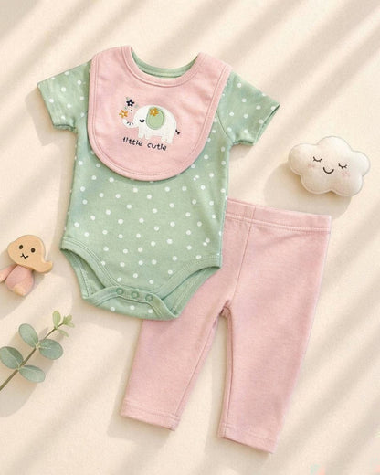 Baby outfit with green onesie, pink pants, and bib on a beige background