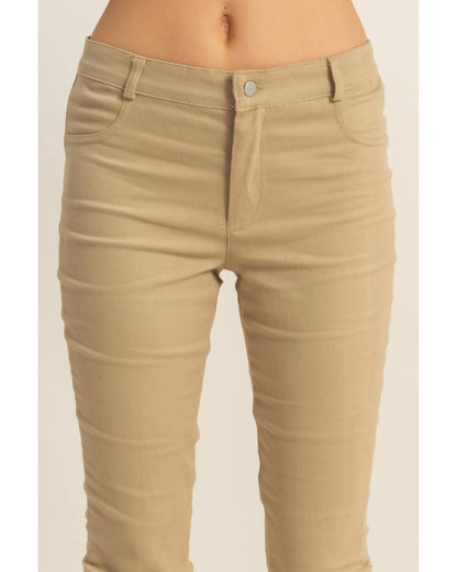 Beige slim-fit denim jeans shown on a model from the waist down, featuring a silver button closure and classic five-pocket design.